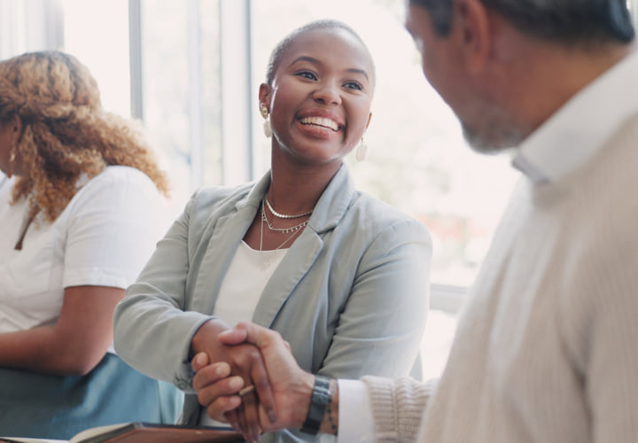 Smiling woman shaking hands with a coworker