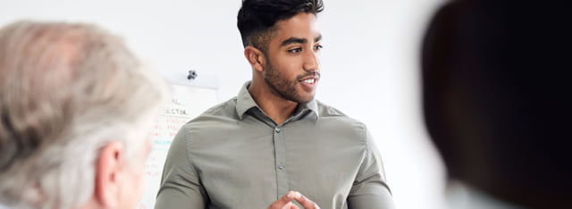 Man standing and presenting information to a group of coworkers.