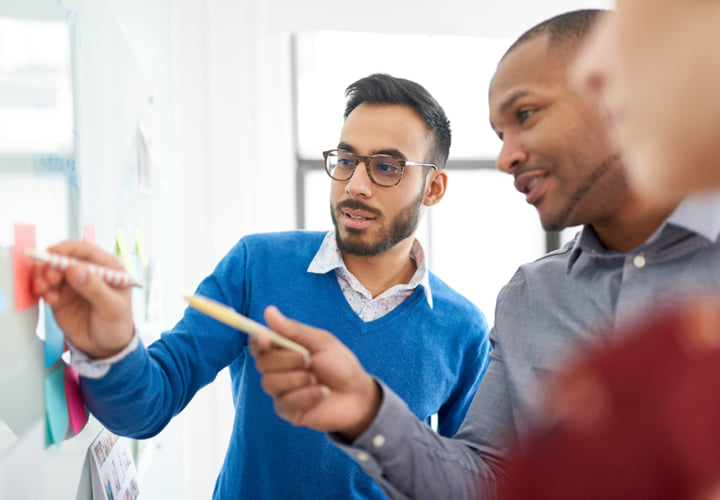 Two coworkers reviewing sticky notes.