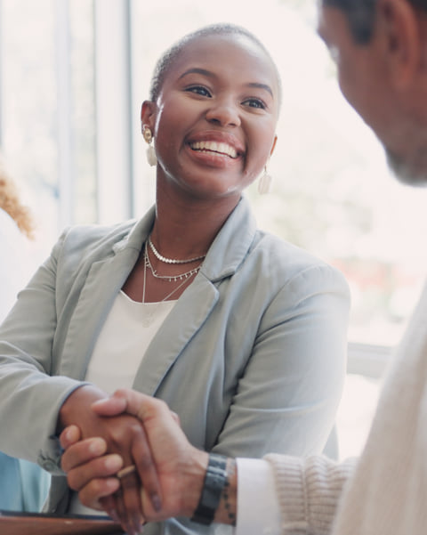 Woman smiling while shaking hands with a coworker