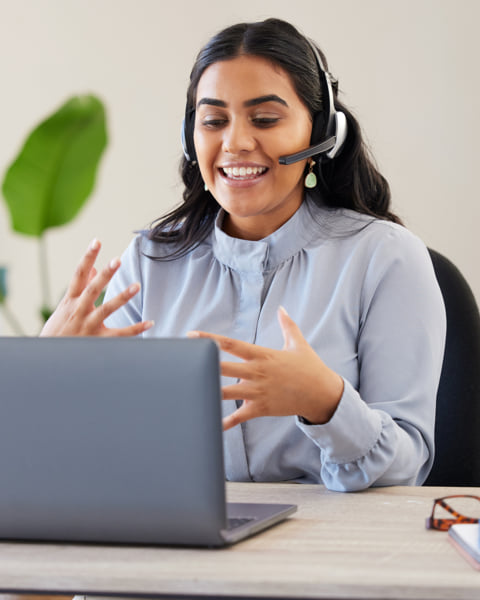 Woman wearing a headset and speaking into a computer.