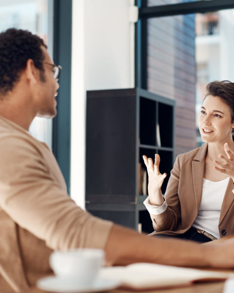 Two coworkers chatting over a desk.