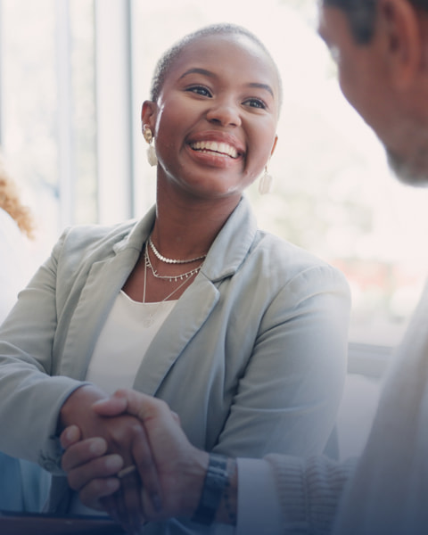 Woman smiling while shaking hands with a coworker