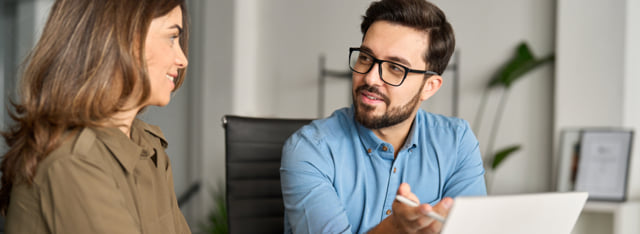 Two coworkers reviewing something on a laptop.