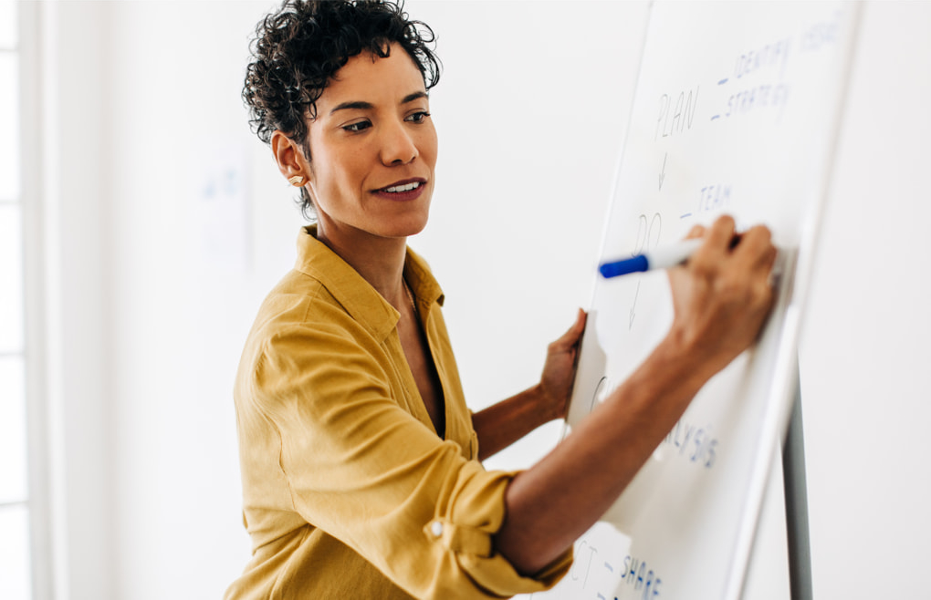 Woman writing something on a whiteboard.