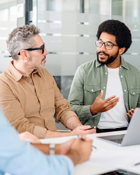 Two coworkers chatting in a contemporary office setting.