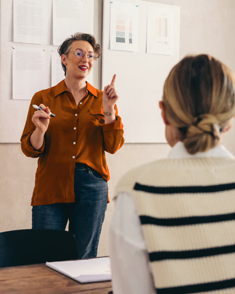 Woman presenting in front of a room full of people.