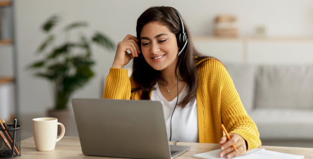 Woman wearing a headset and working at a laptop computer.