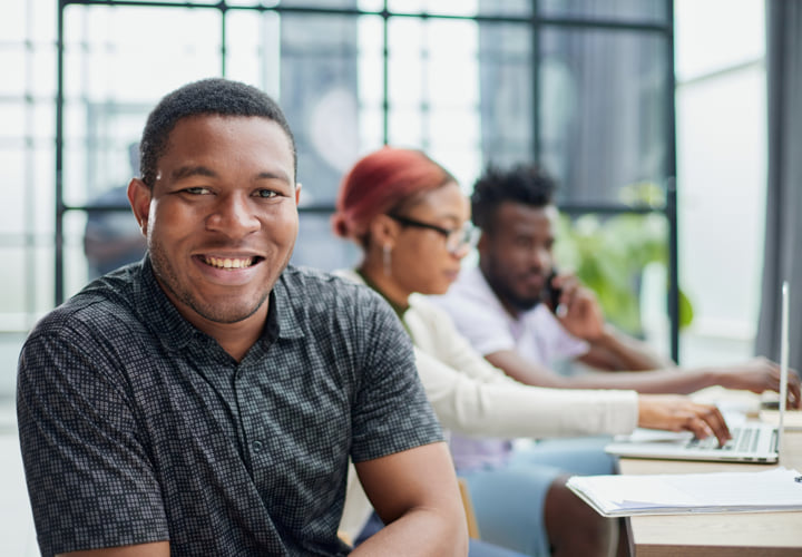 Young man student smiling in a library setting.