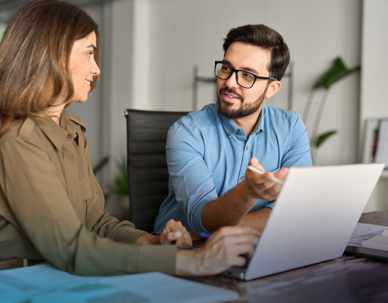 A man and a woman reviewing something on a laptop.