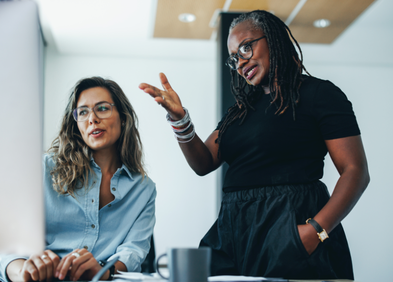 Two women working together in a contemporary office setting.