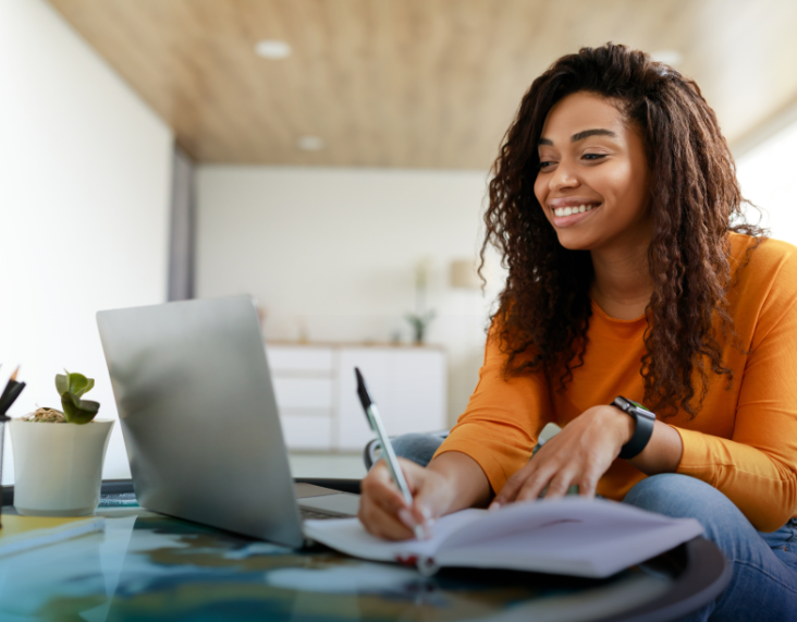 Young female student writing in a notebook while looking at a laptop. A sample Student LPI Self report is in the bottom left corner.